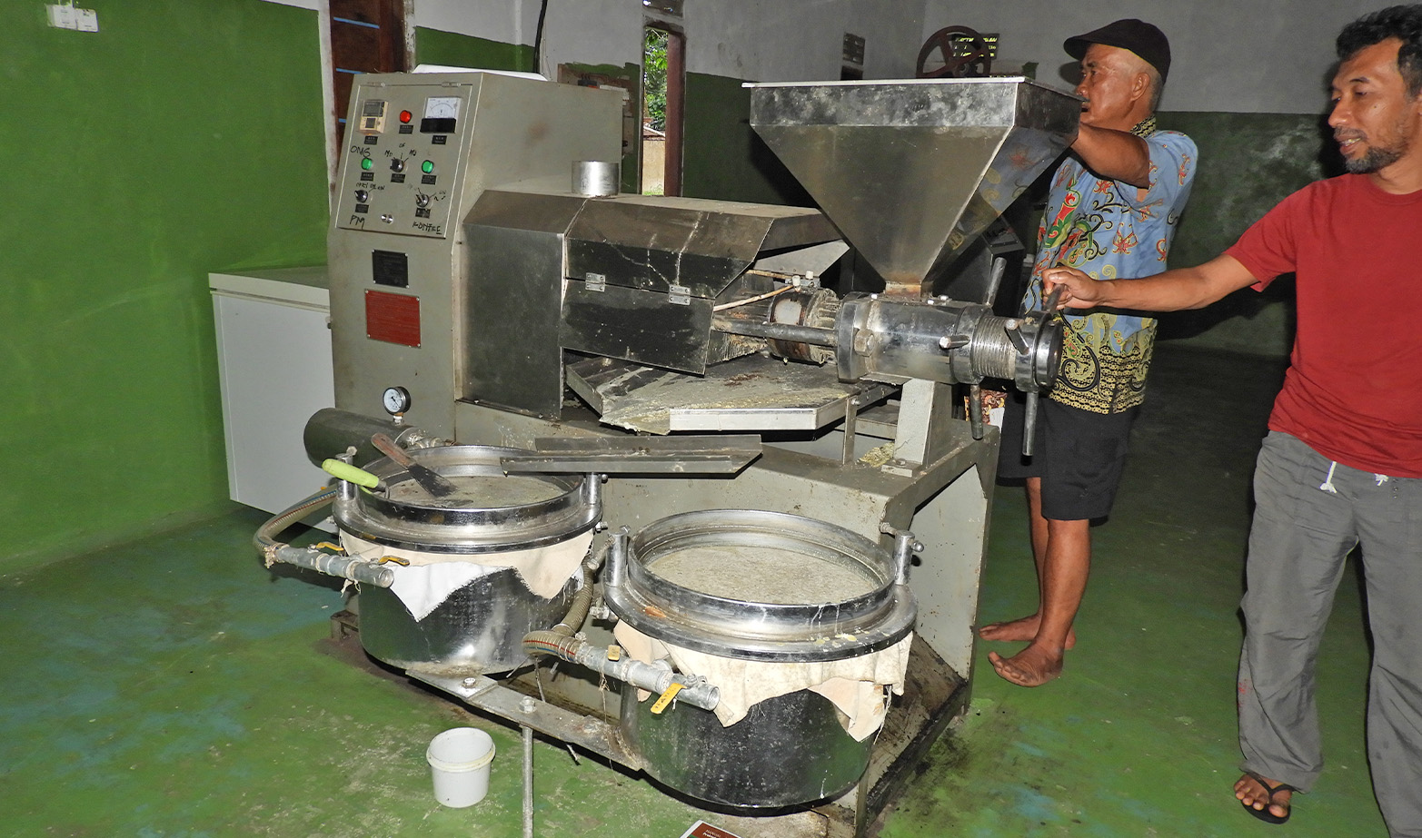 Damianus Nadu (Desa Sahan, left) and Deman Huri (INTAN, right) with the tengkawang processing machine in the tengkawang butter factory, Desa Sahan